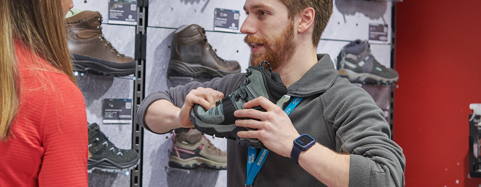 A shop expert is holding a boot in his hands