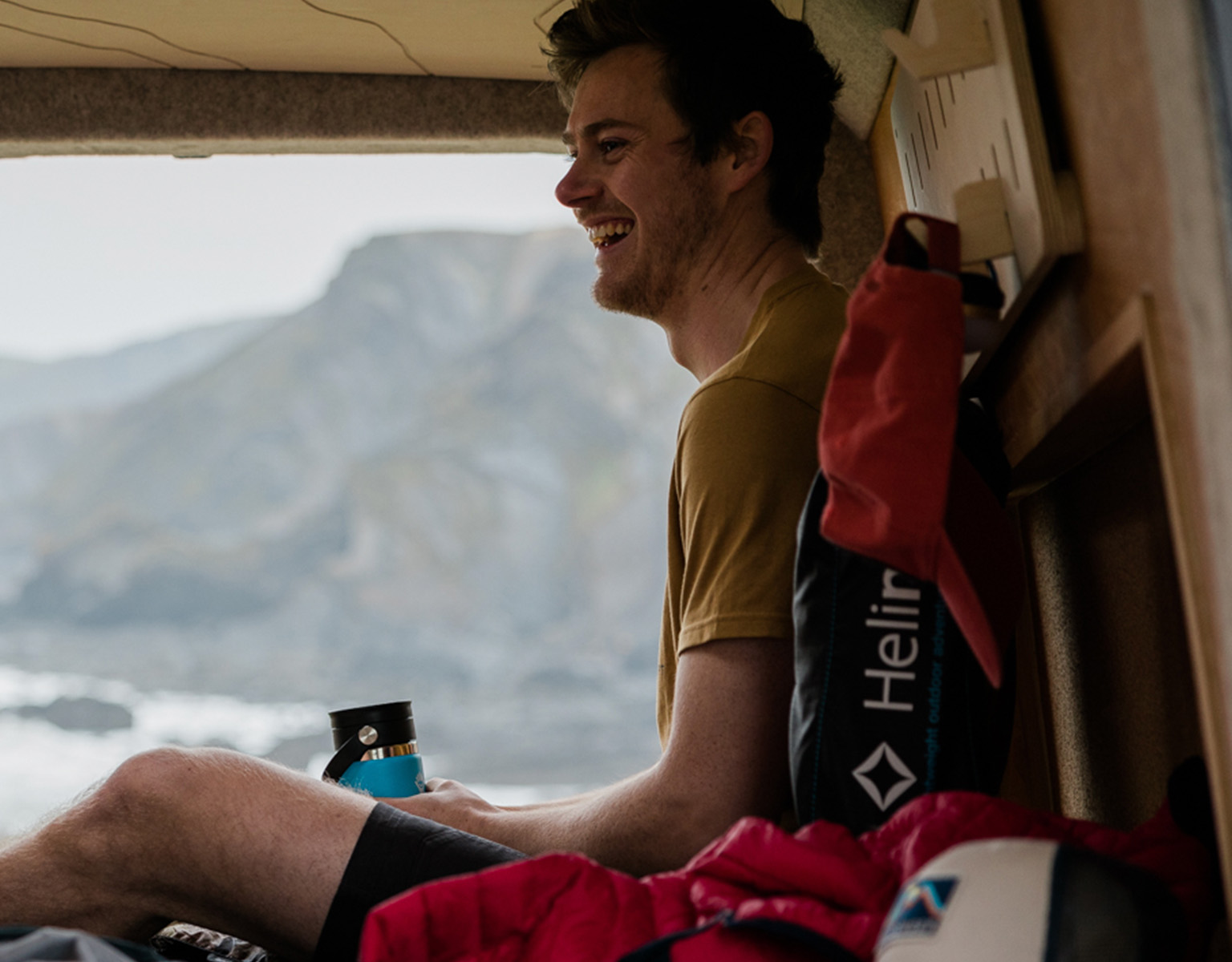 A man is sitting in a tent and holding a blue water bottle.