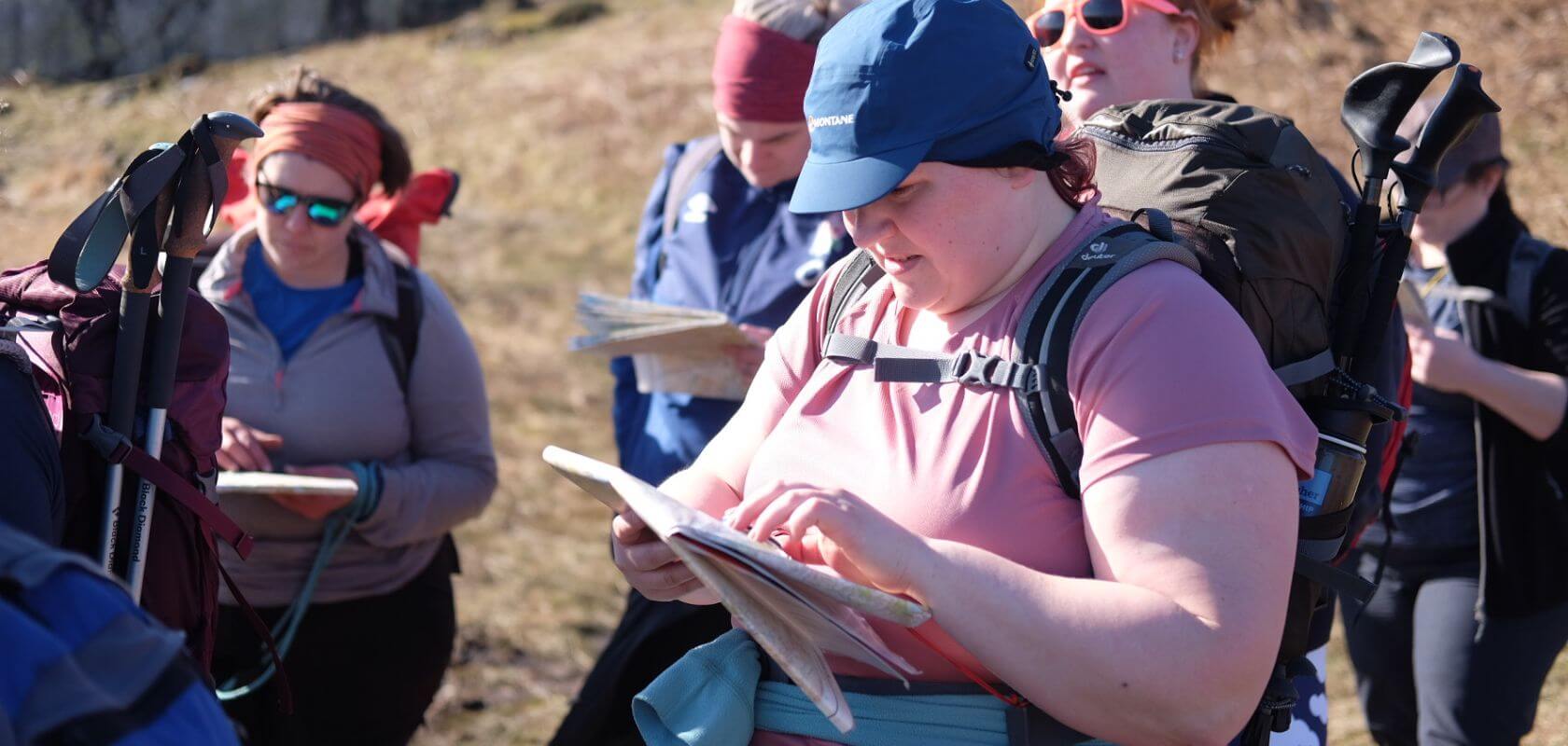 Person studying an ordnance map during a hike with freinds. 