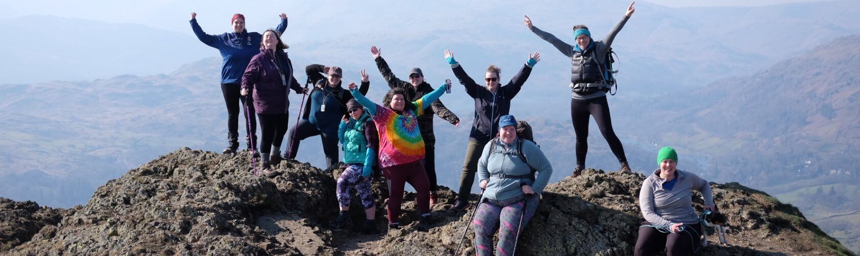 Hikers stood on a mountain peak with their arms raised in celebration