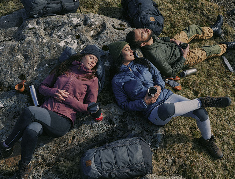 three people relaxing on a rock