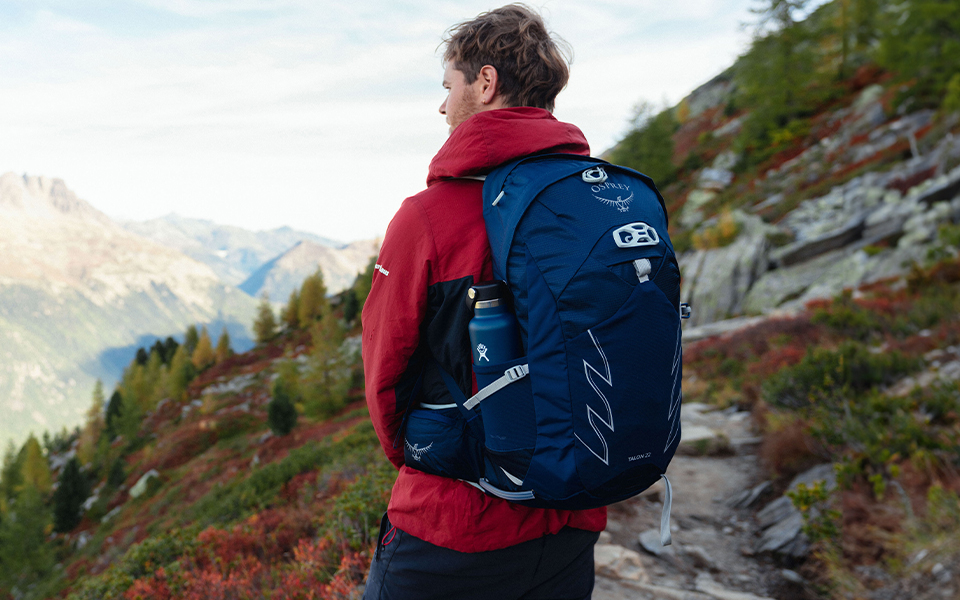 A man looking out at the beautiful mountain scenery wearing an Osprey pack 