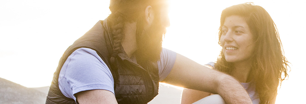 A man wearing a gilet watching the sunset with his wife 