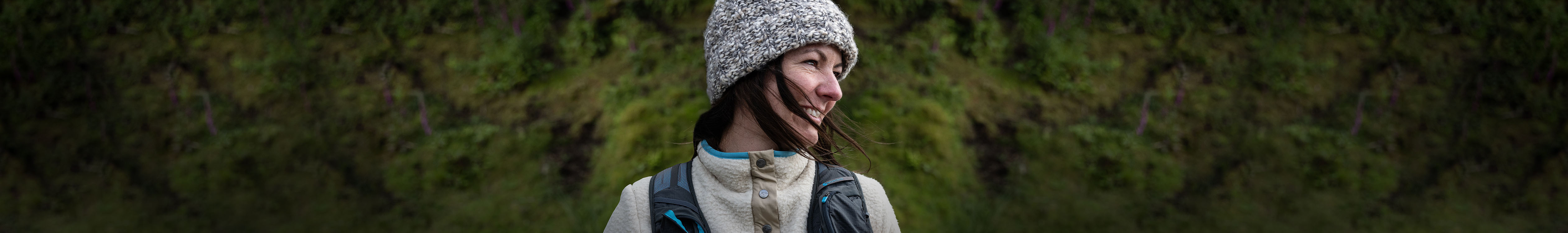 A woman is rearing a grey hat and carrying a rucksack