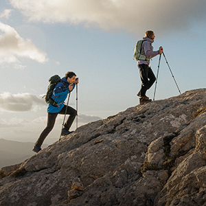 Man and woman hiking up a mountain wearing packs