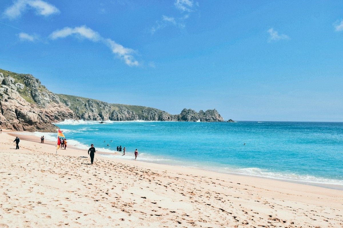 People on Porthcurno beach on a sunny day