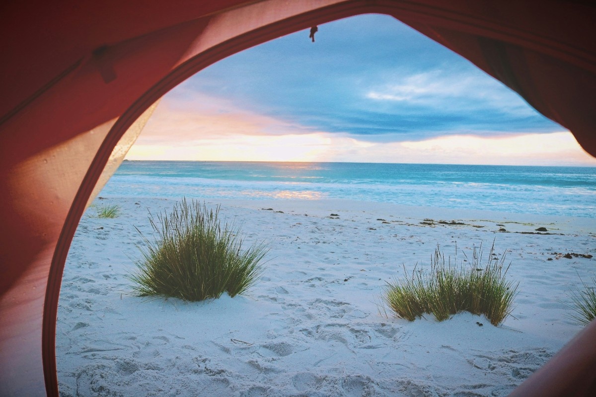 An image taken through the door of a tent, looking out onto the beach 