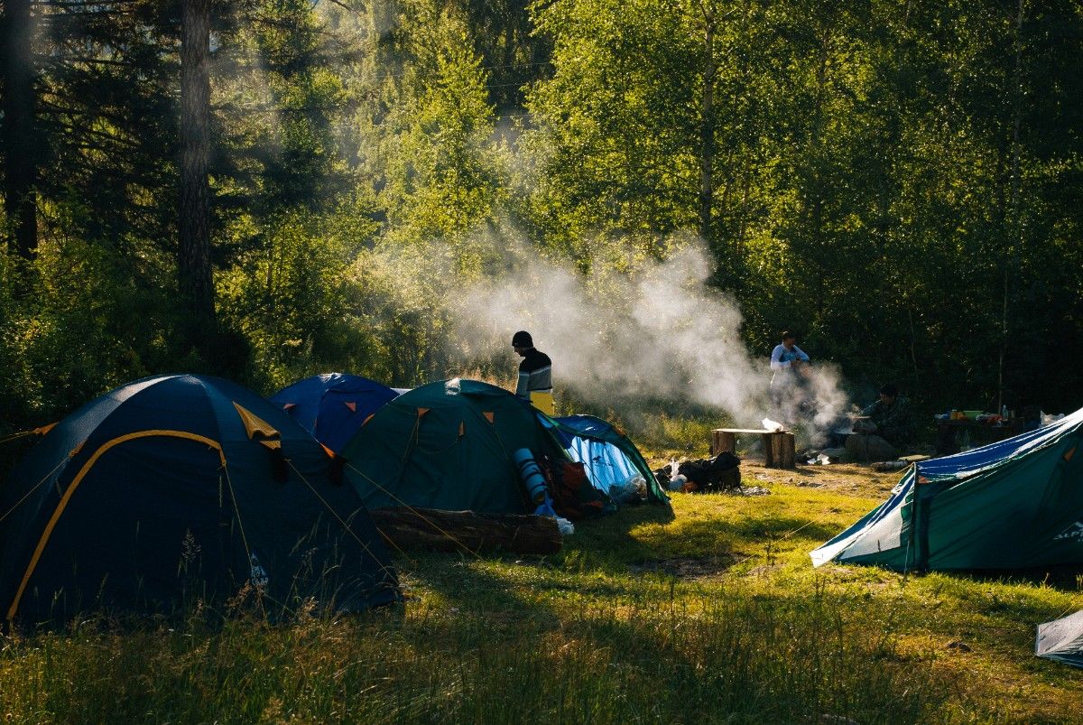 An image of a campsite with the distant smoke of a fire cooking dinner