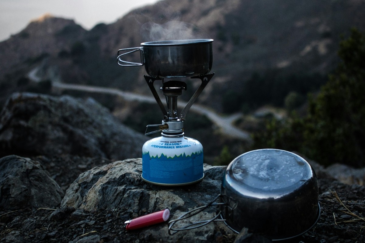 A camp stove boiling a pan of water 