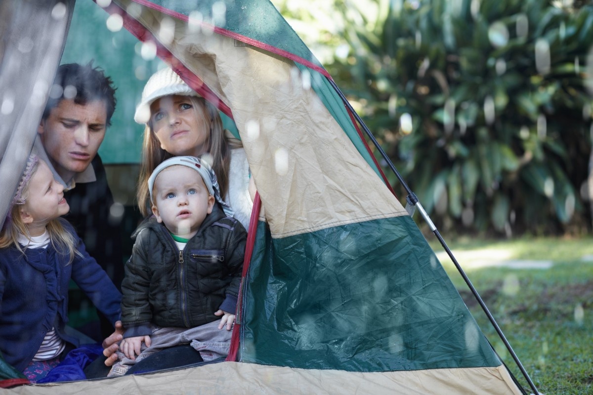 A family watching the rain from their tent 