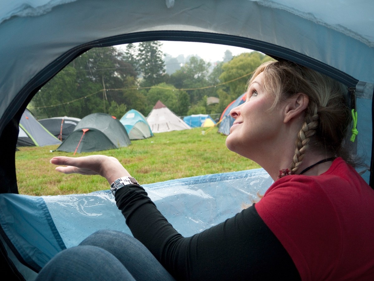 A person checking the rain outside their tent 