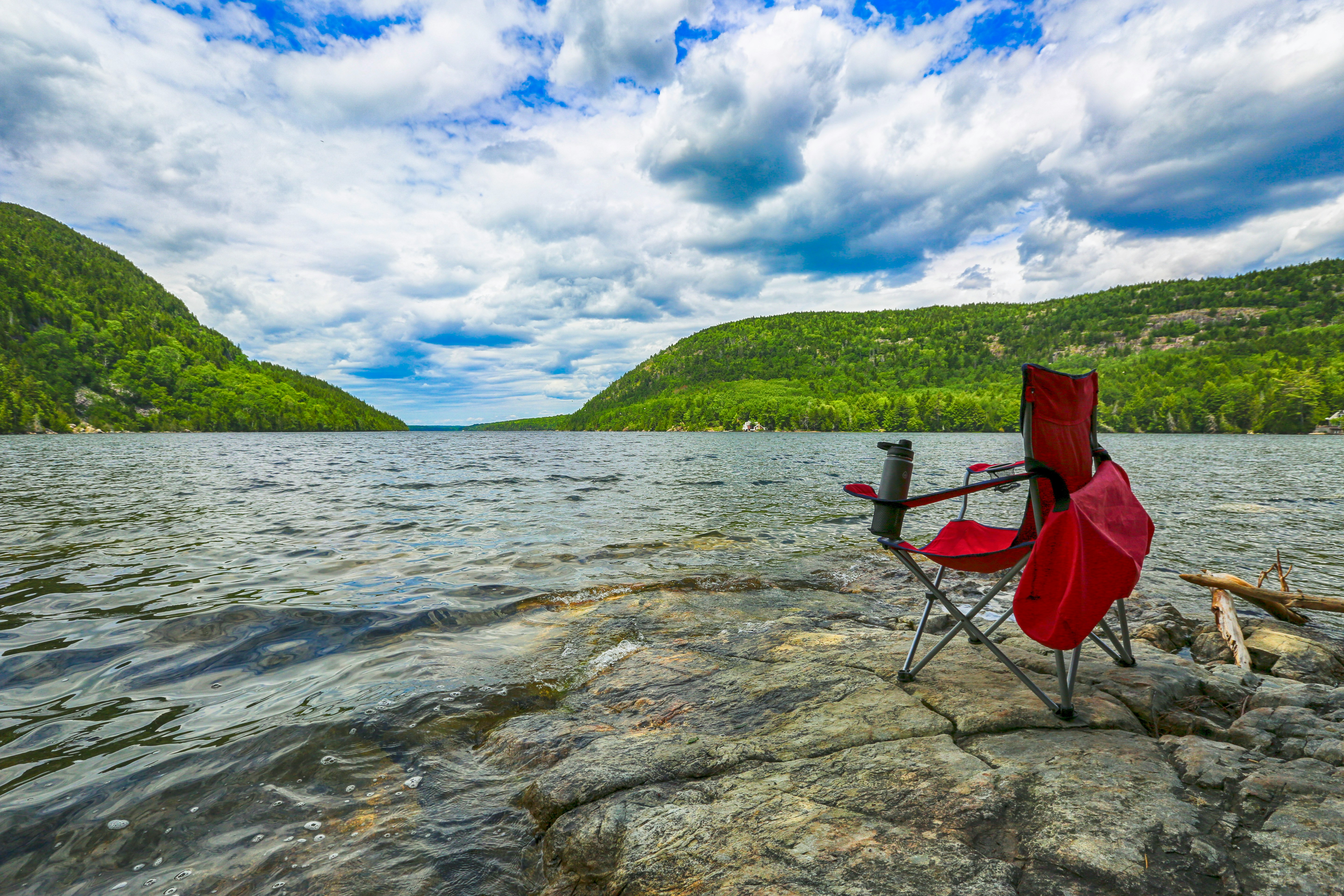 A camp chair pitched up by a lake