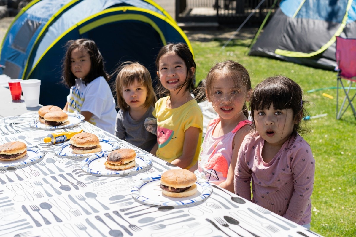 A group of girls eating burgers on a family camping trip 