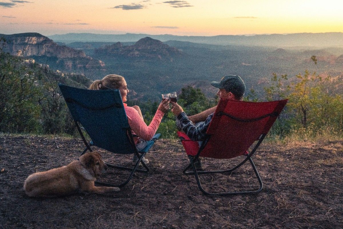 A man, woman and their dog in a camp chair 