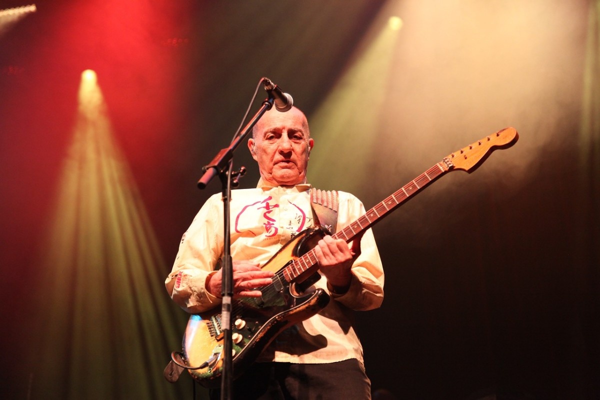 A man performing with his guitar on stage 