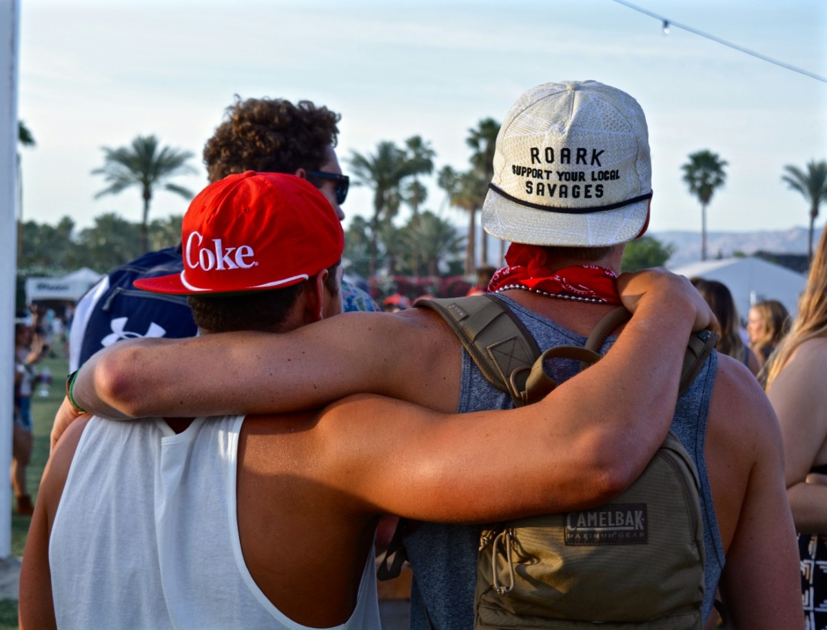 Two friends with their arms round each others shoulders in the crowd at Coachella 