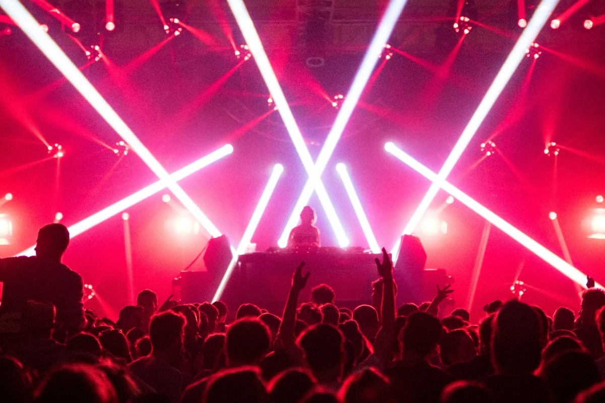 A DJ performing on stage at Creamfields, with red lasers above the crowd 