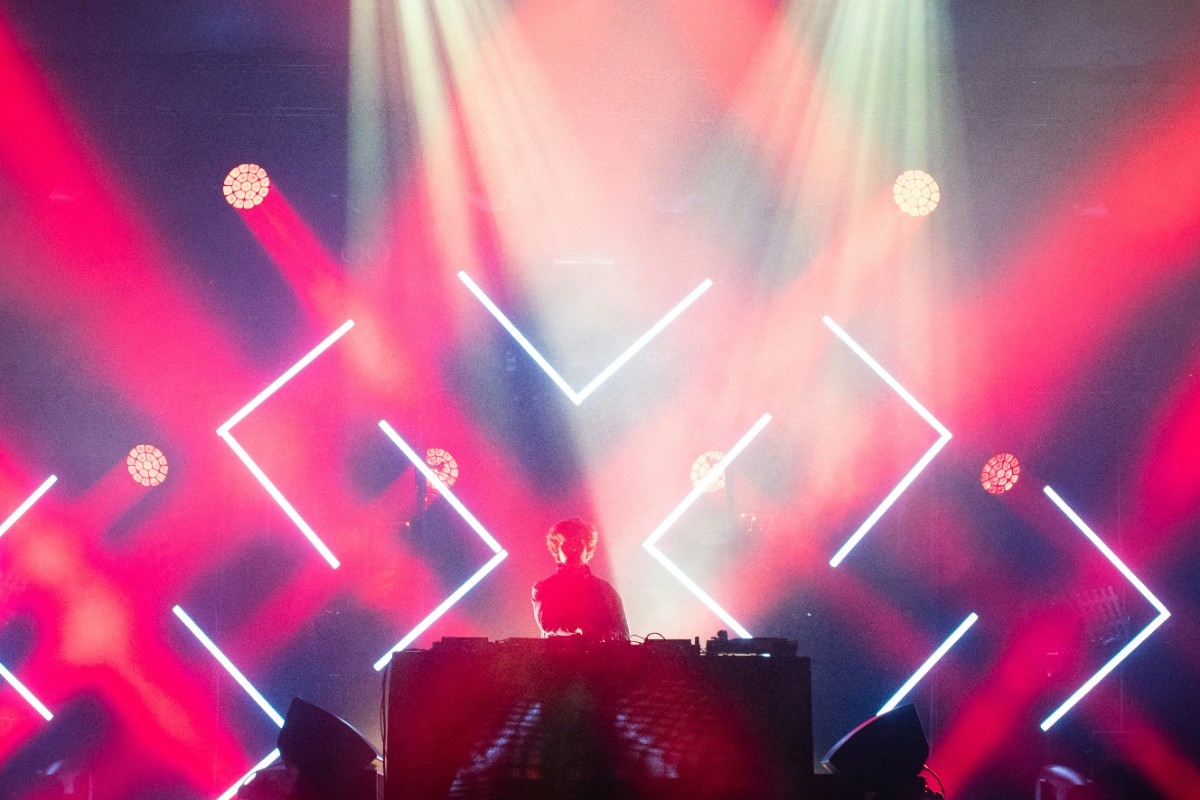 A DJ performing on stage at Creamfields, with red lasers above the crowd 