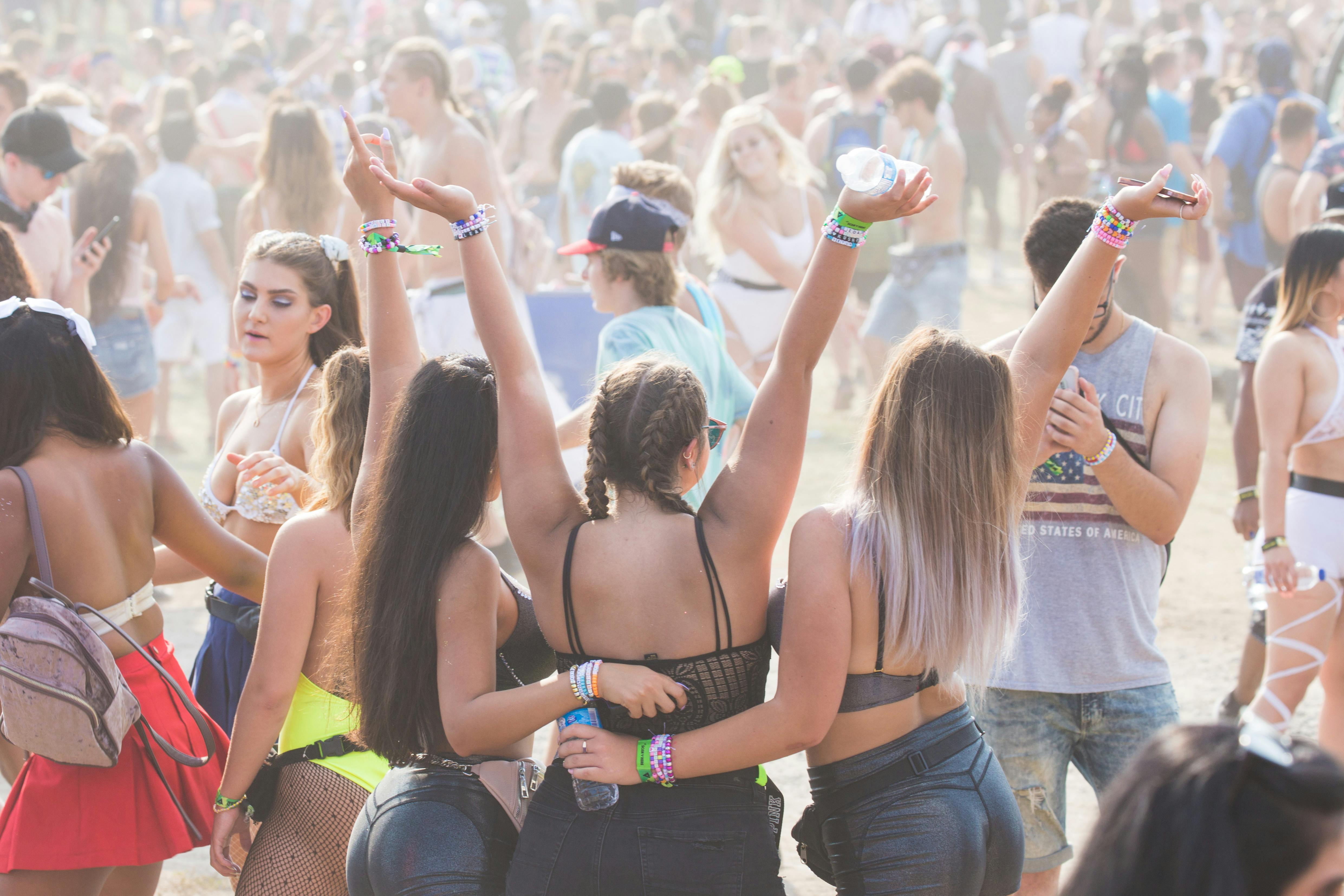 Three girls hugging each other in a crowd at the festival 