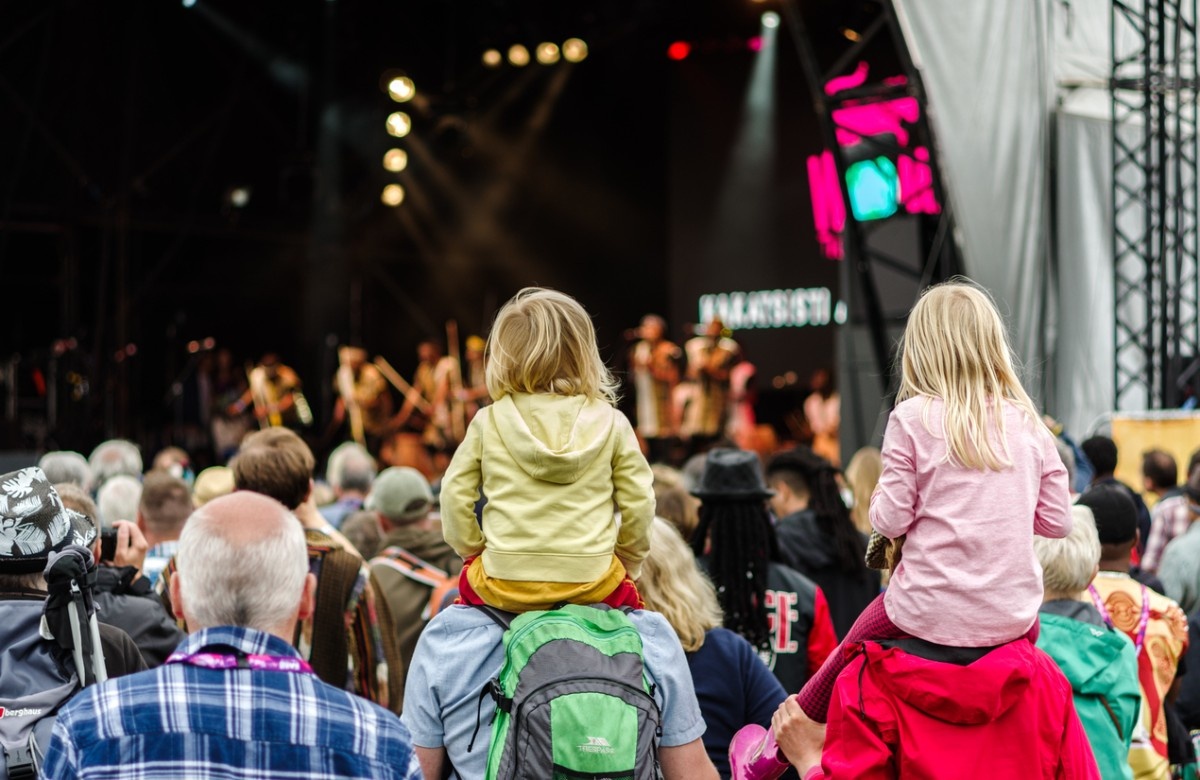 Kids on their dad shoulders whilst a jazz band performs on stage at We Out Here Festival 