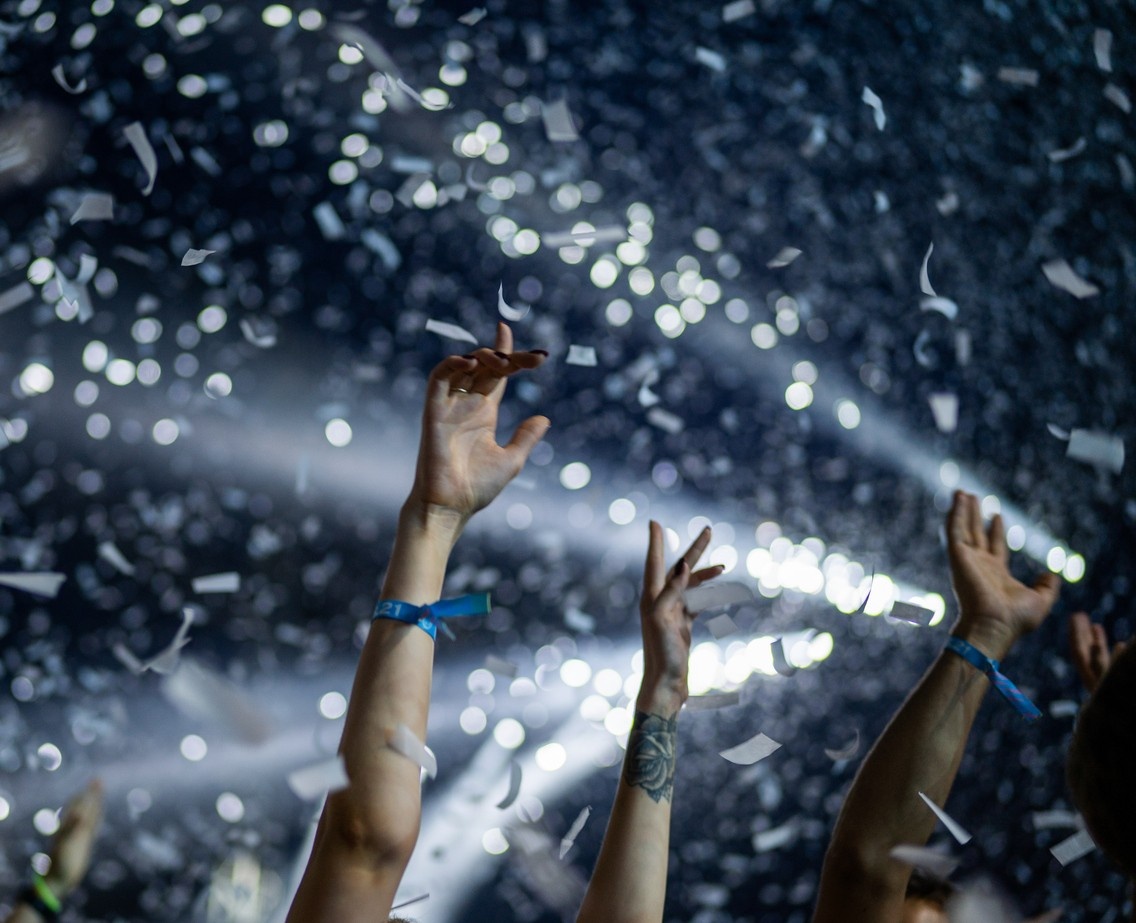 People with their hands in the air, confetti over the crowd 