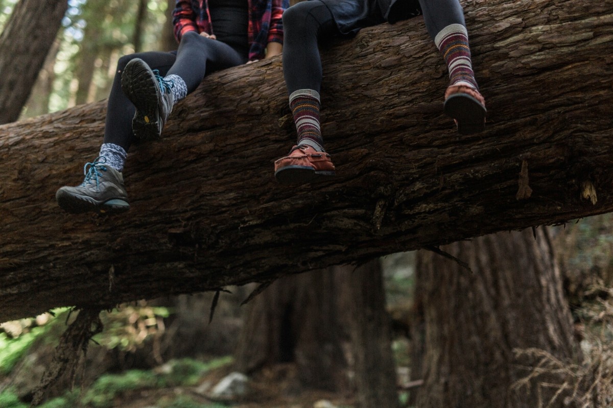 A person sat on a log with their hiking socks out 