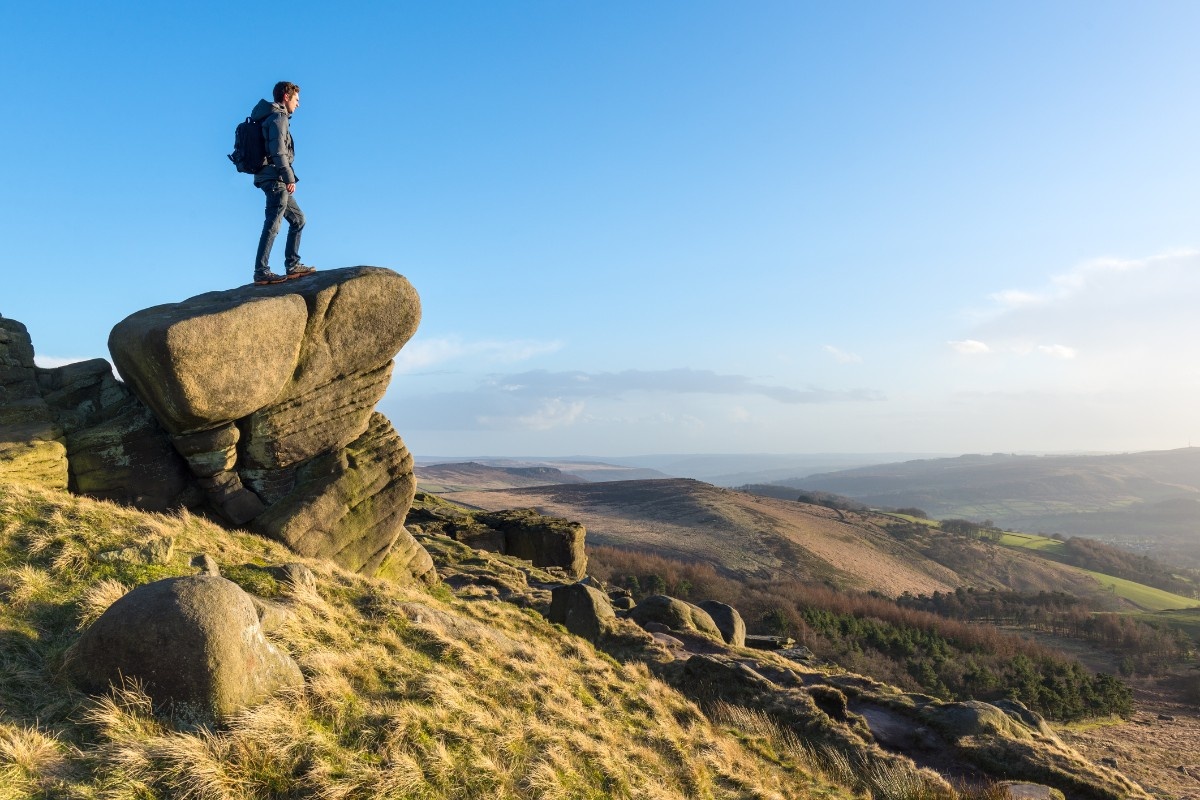 A person standing on a rock looking out from Stanage Edge 