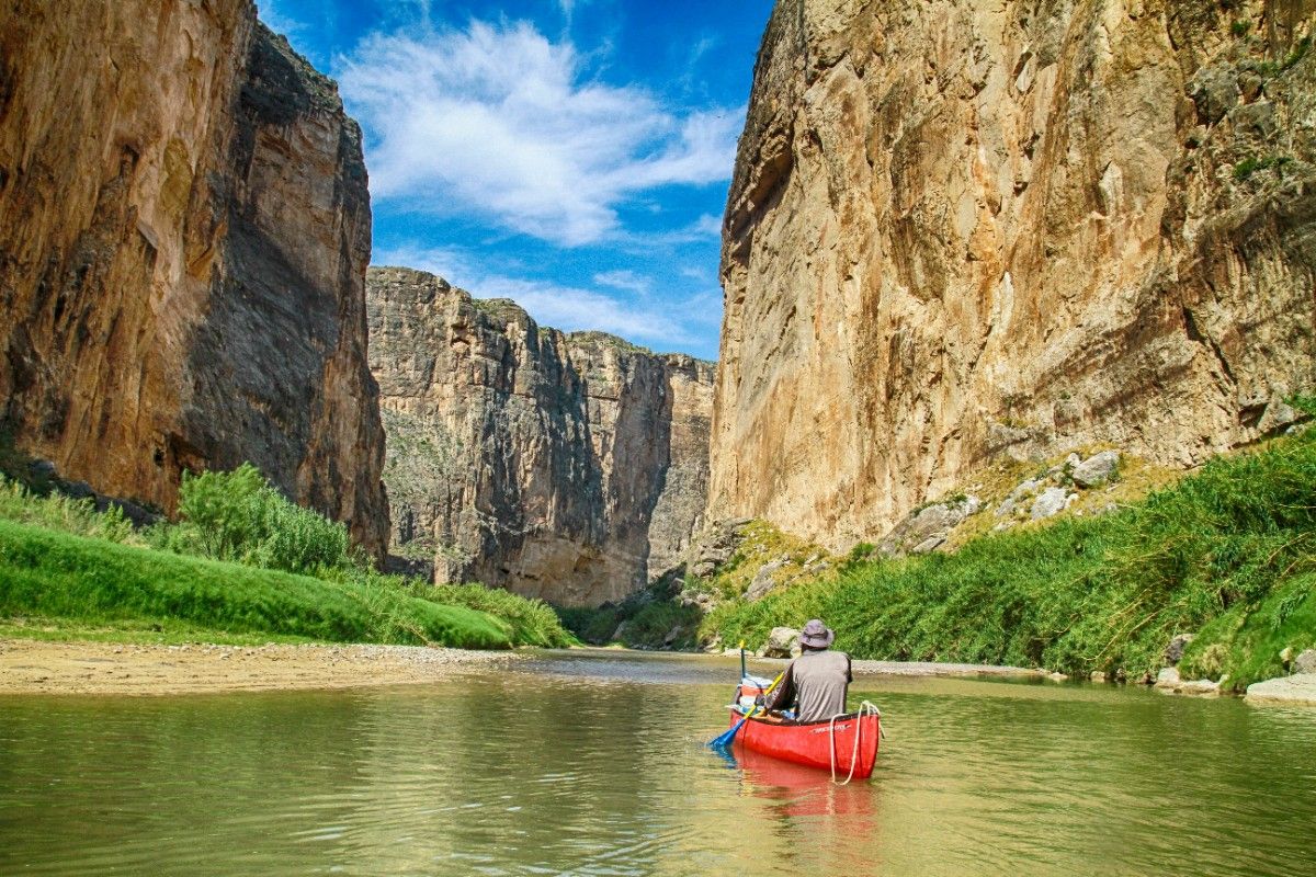 A person canoing on a river through Big Bend Canyon