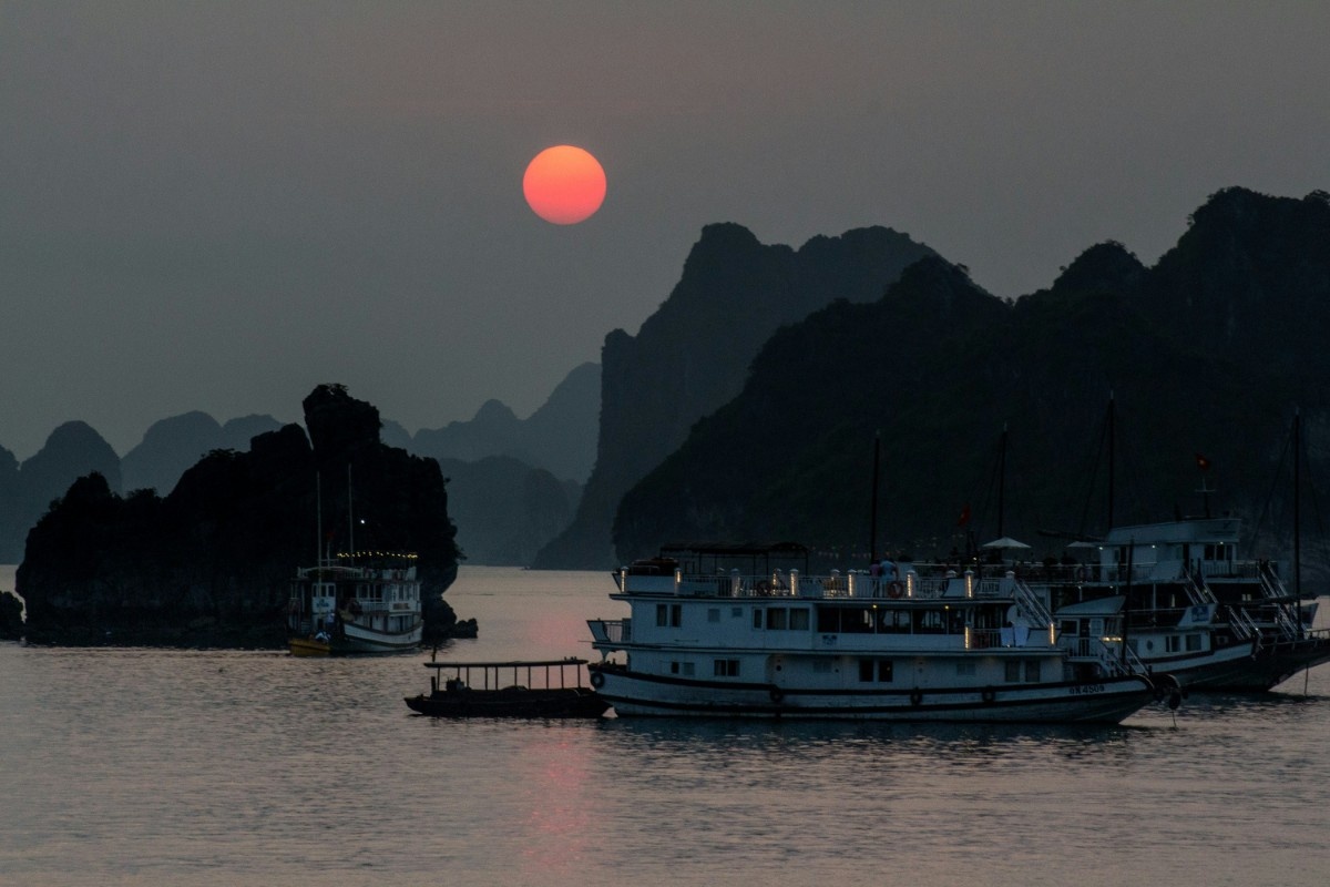 The sun setting over Ha Long Bay, Vietnam with a boat on the water