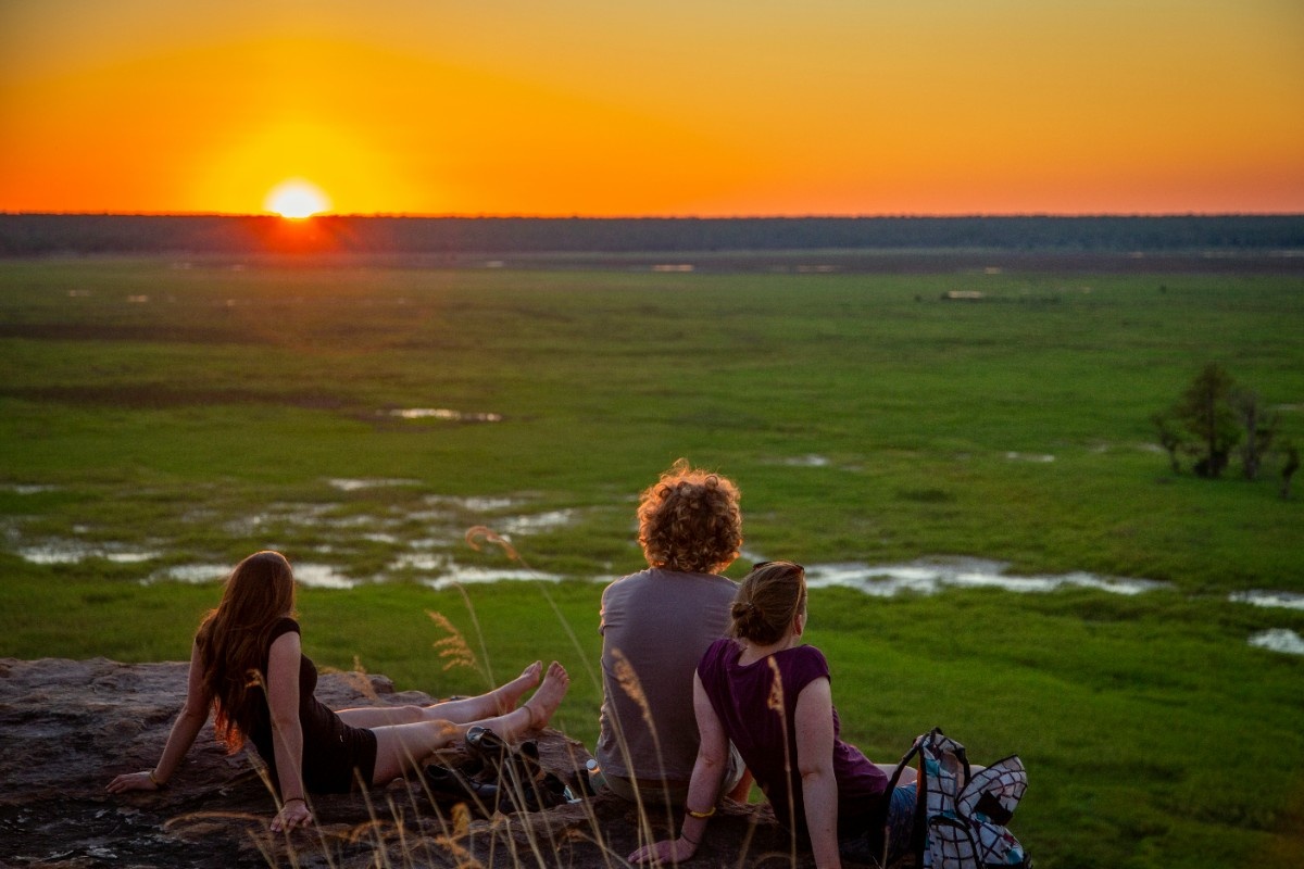 Three people sat watching the sunset in Kakadu National Park 