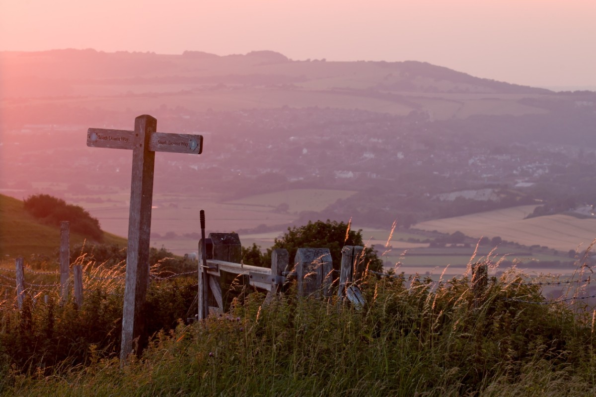 A signpost with the sun setting over the South Downs Way