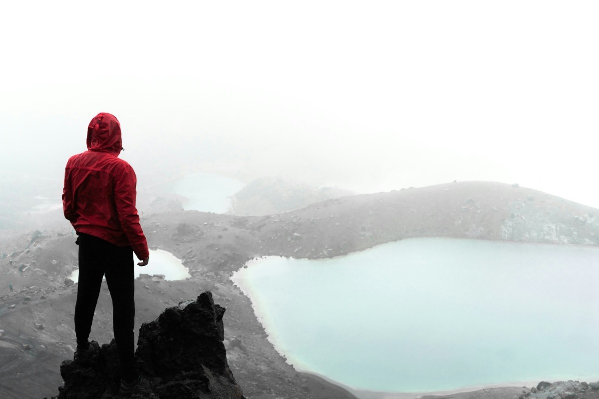 A man looking out onto a lake on the Tongariro Alpine Crossing