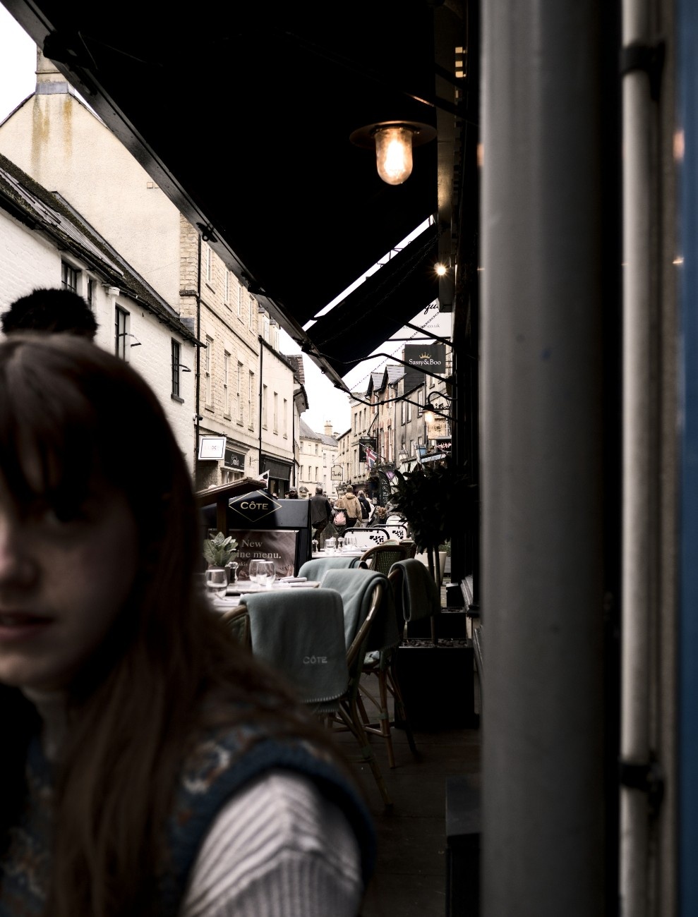 A woman sat outside a restaurant in a street in Cirencester