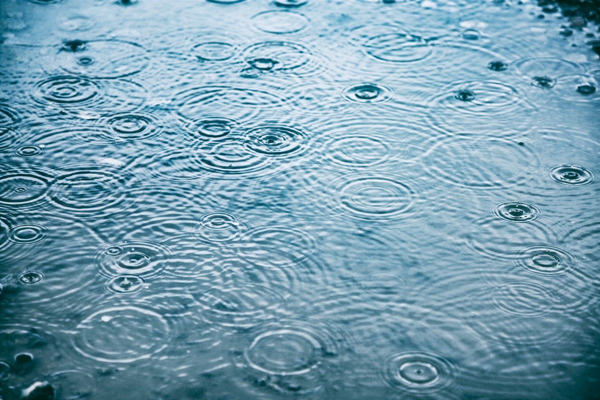 Water pooling on the ground with raindrops falling