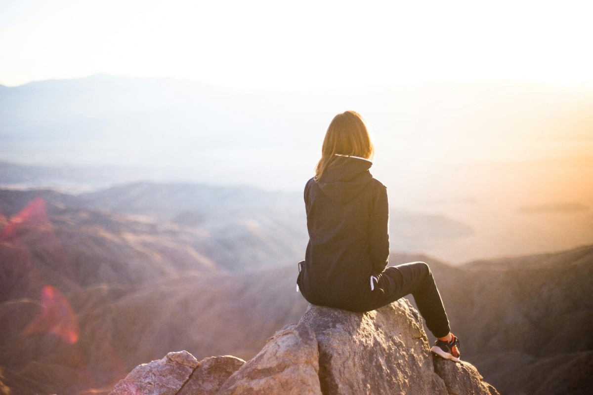 A woman sat practicing mindfulness on a mountain edge