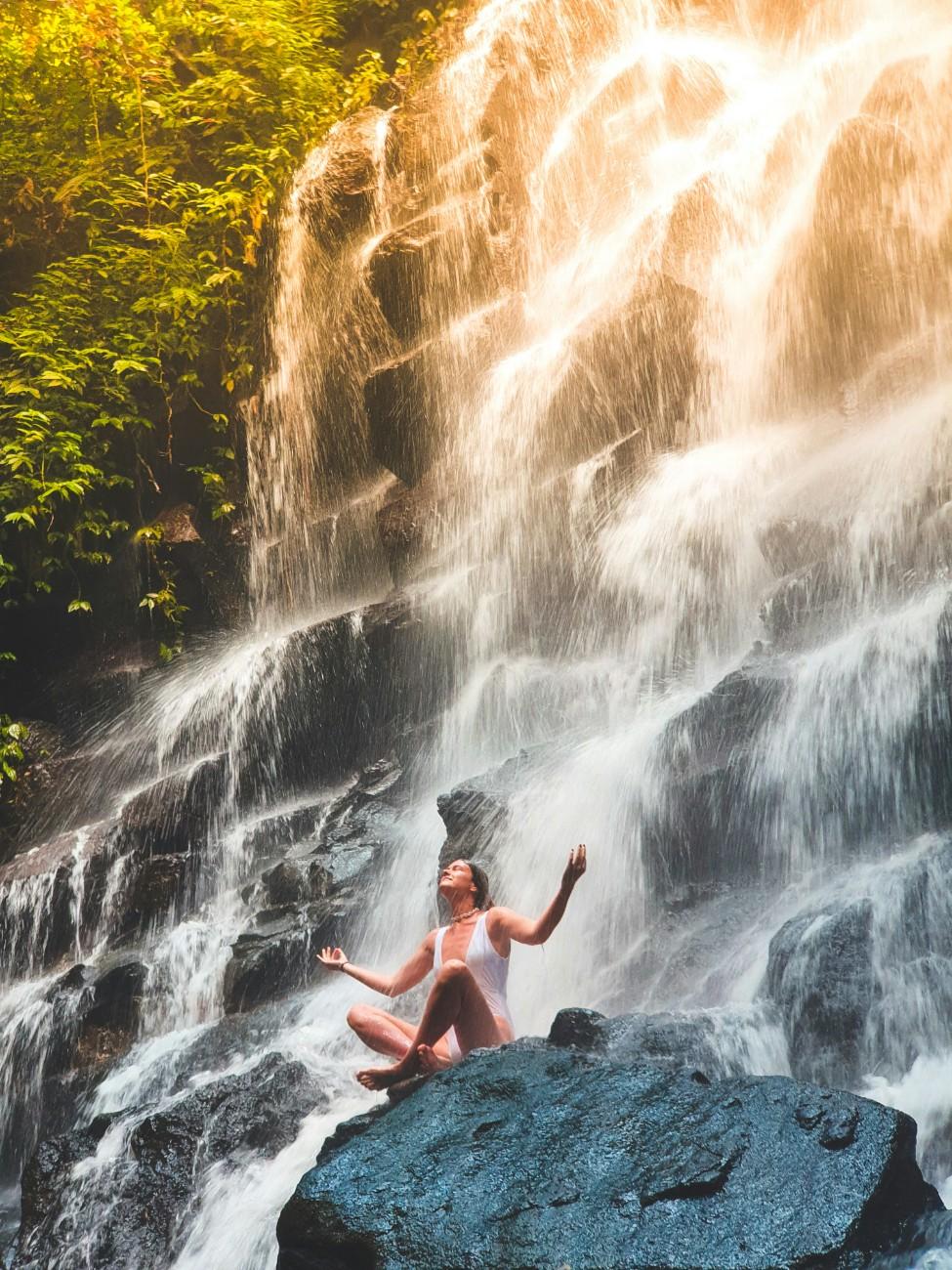 A woman meditating under a waterfall