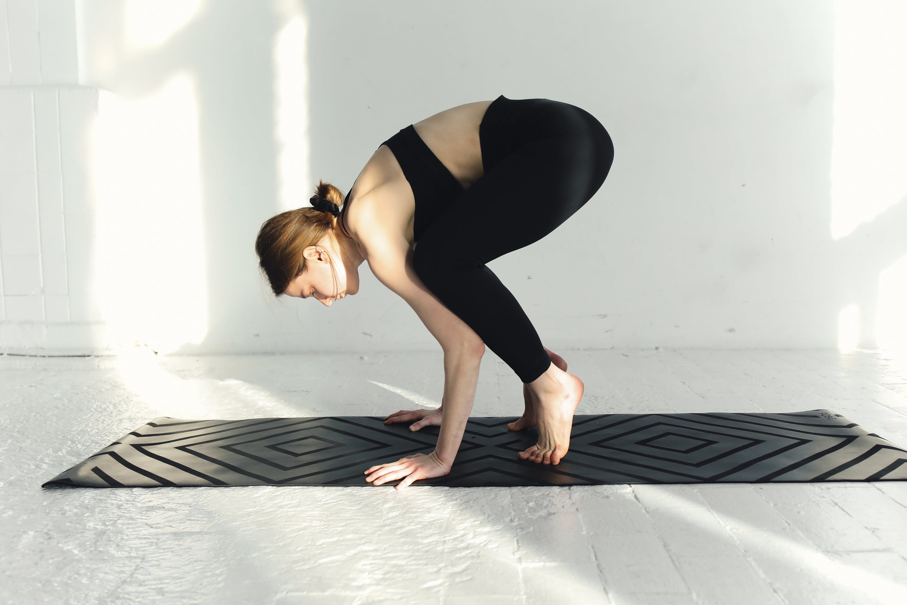 A person preparing to perform a Crow pose in their yoga practice 