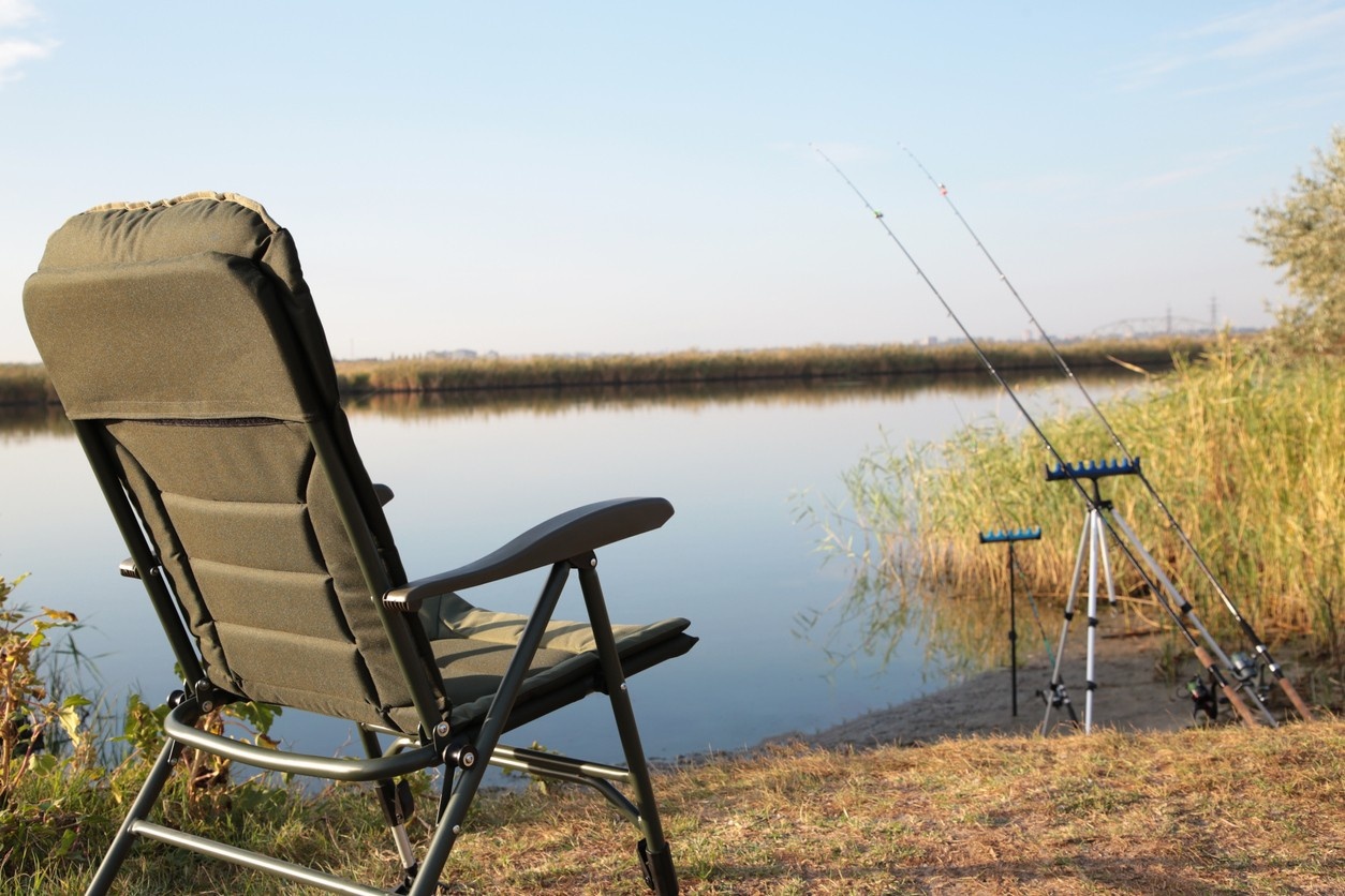 Fisherman's chair and fishing rods in the background over the river at sunrise, foggy morning. 