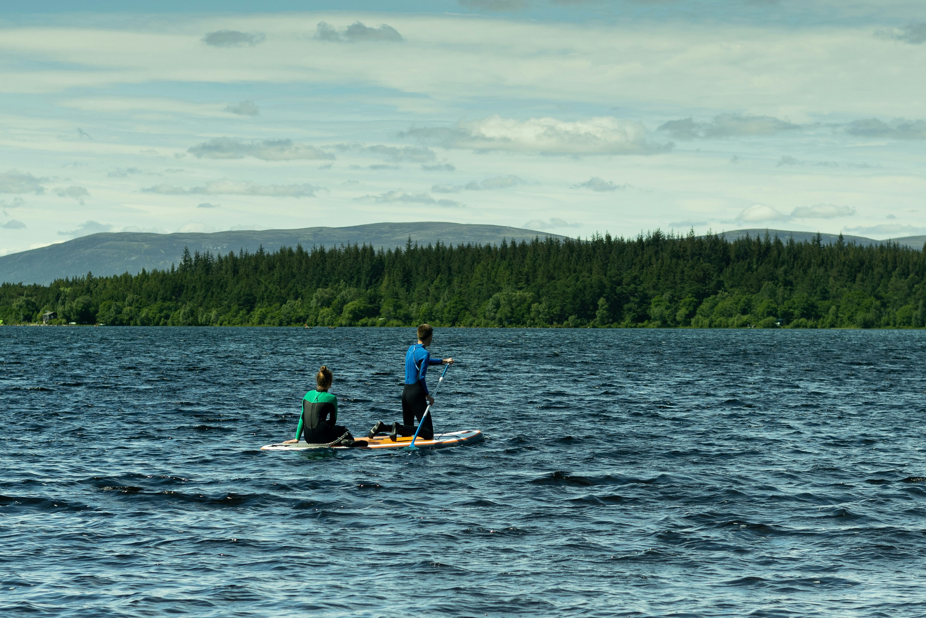 A man and a womanon a paddleboard on Loch Morlich