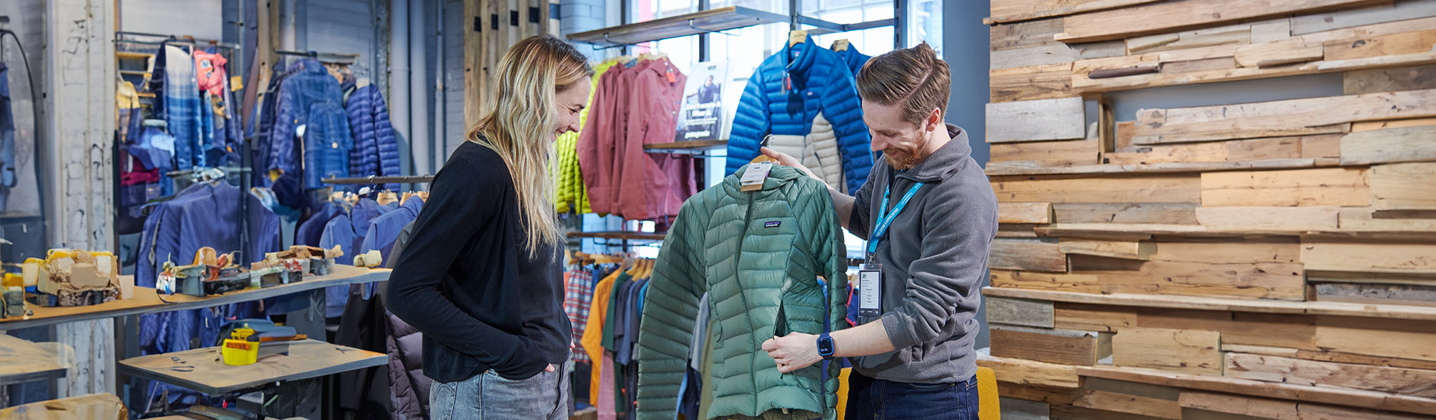 A shop assistant is helping to choose a jacket to a woman