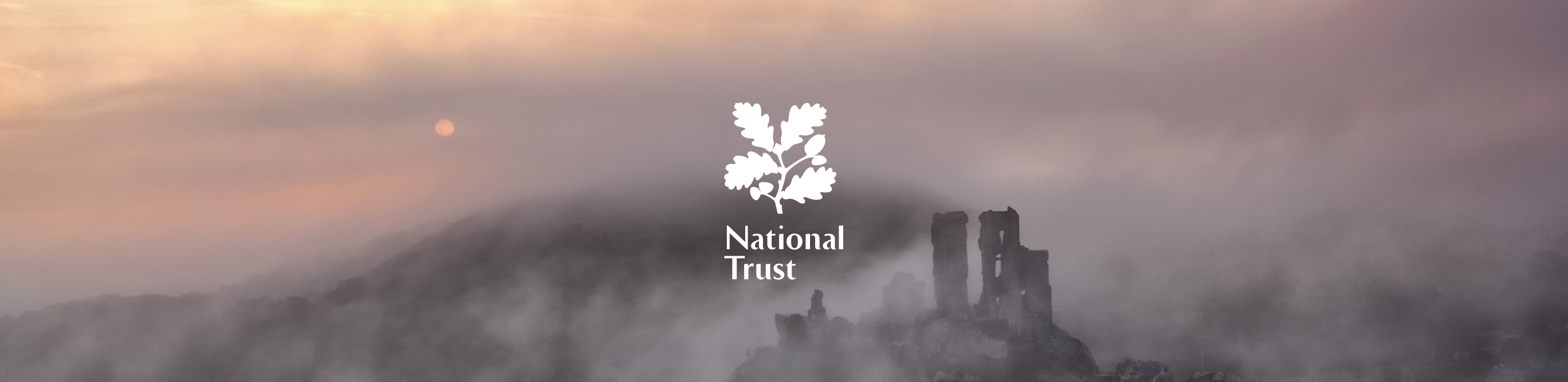 Ruins in mist with the National Trust brand logo in the middle