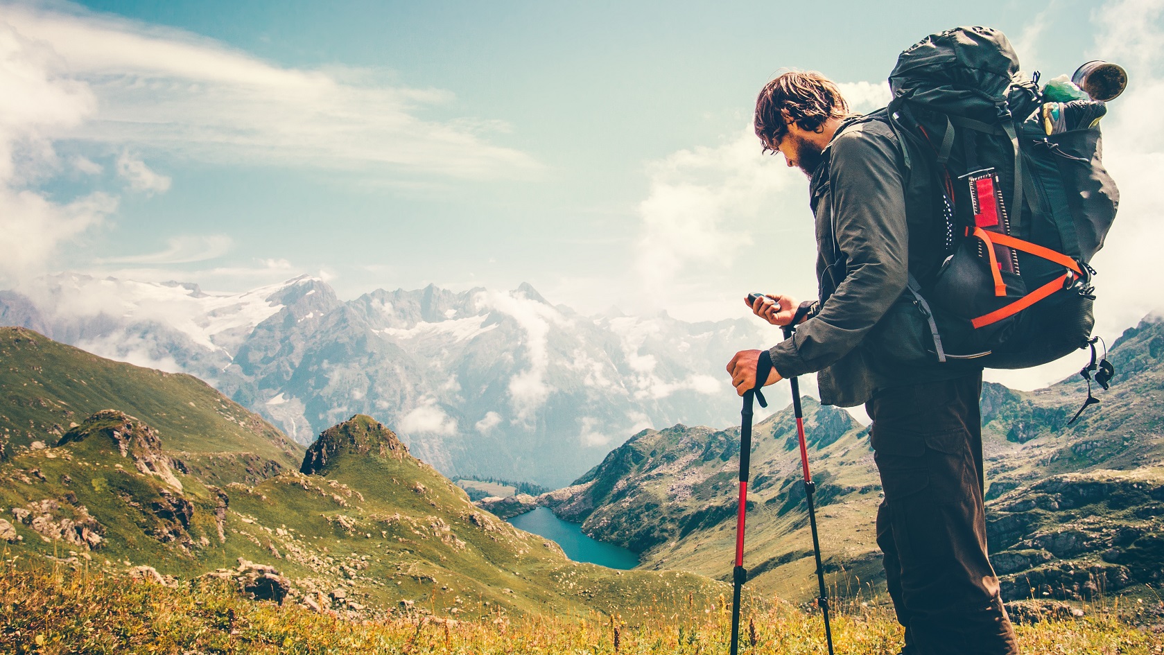 Man Traveler backpacker with gps navigator tracker looking for coordinates Travel Lifestyle concept mountains and lake on background survival adventure vacations outdoor