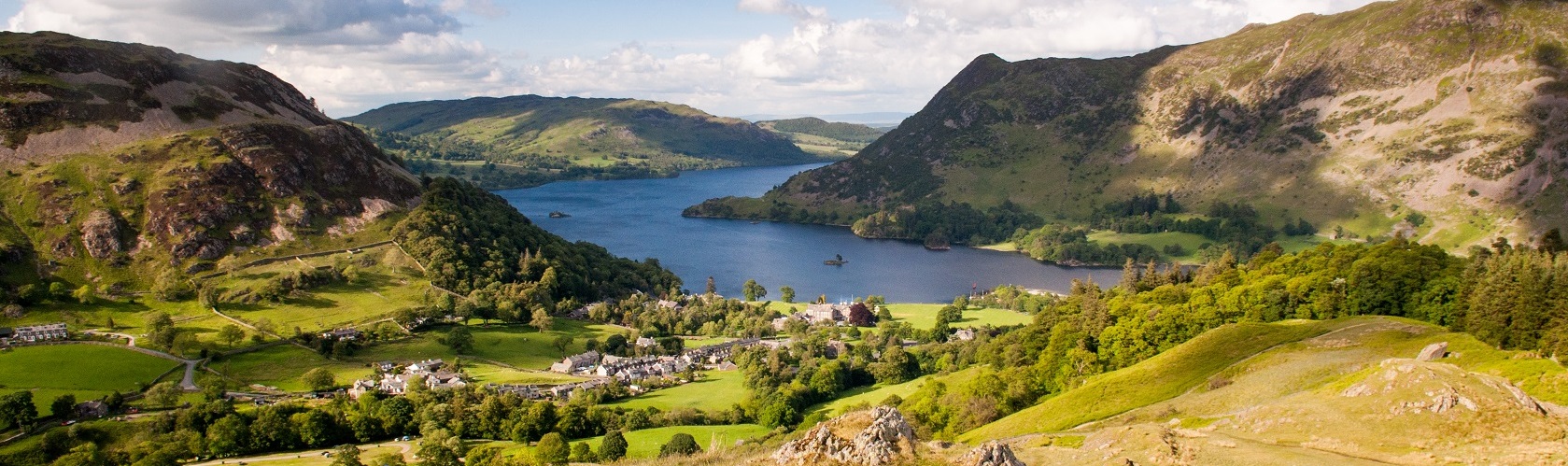 An image of the peaks of the lake district and fields with sheep roaming 